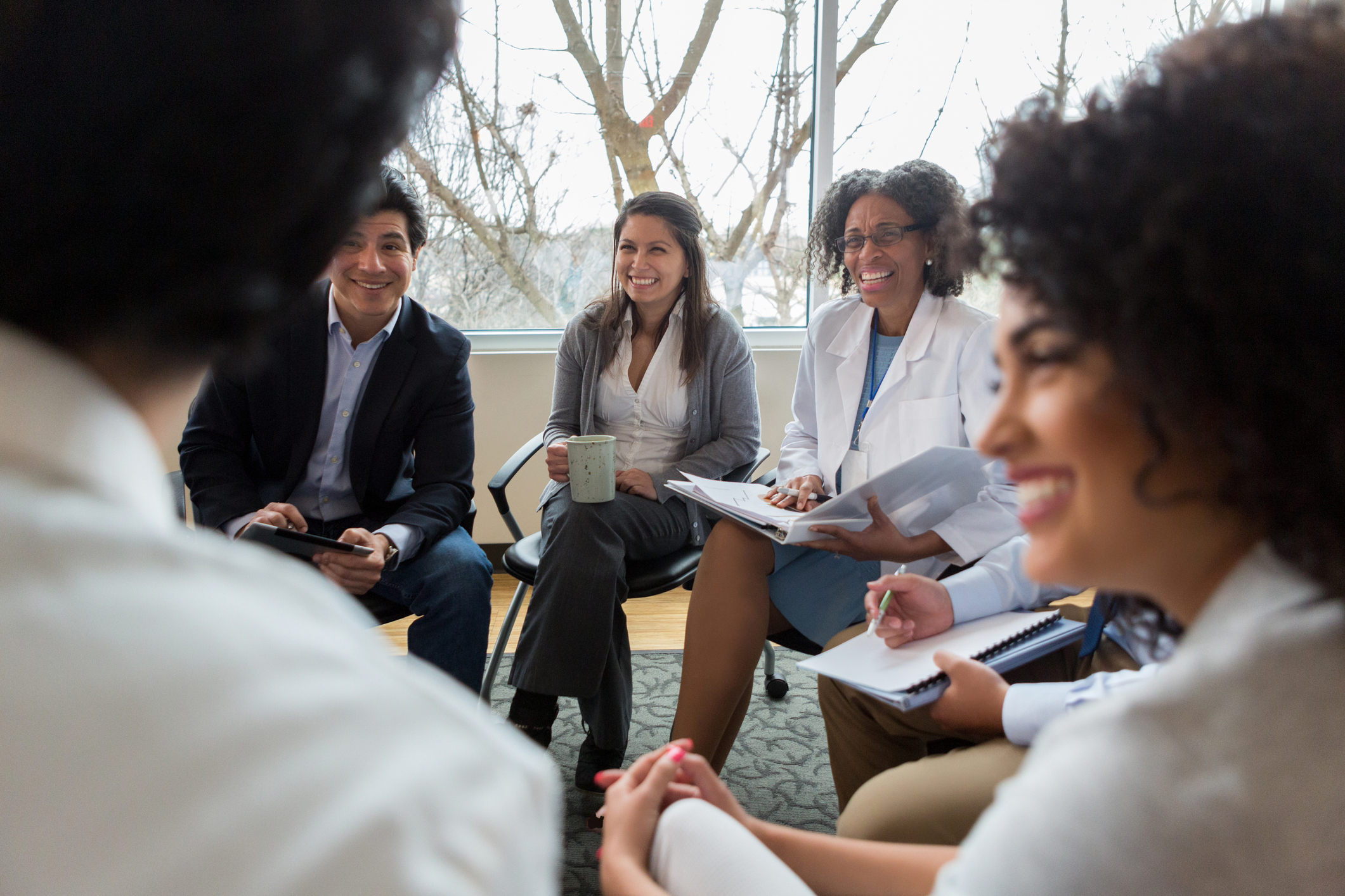 A group of people attending group therapy sitting in a circle and smiling