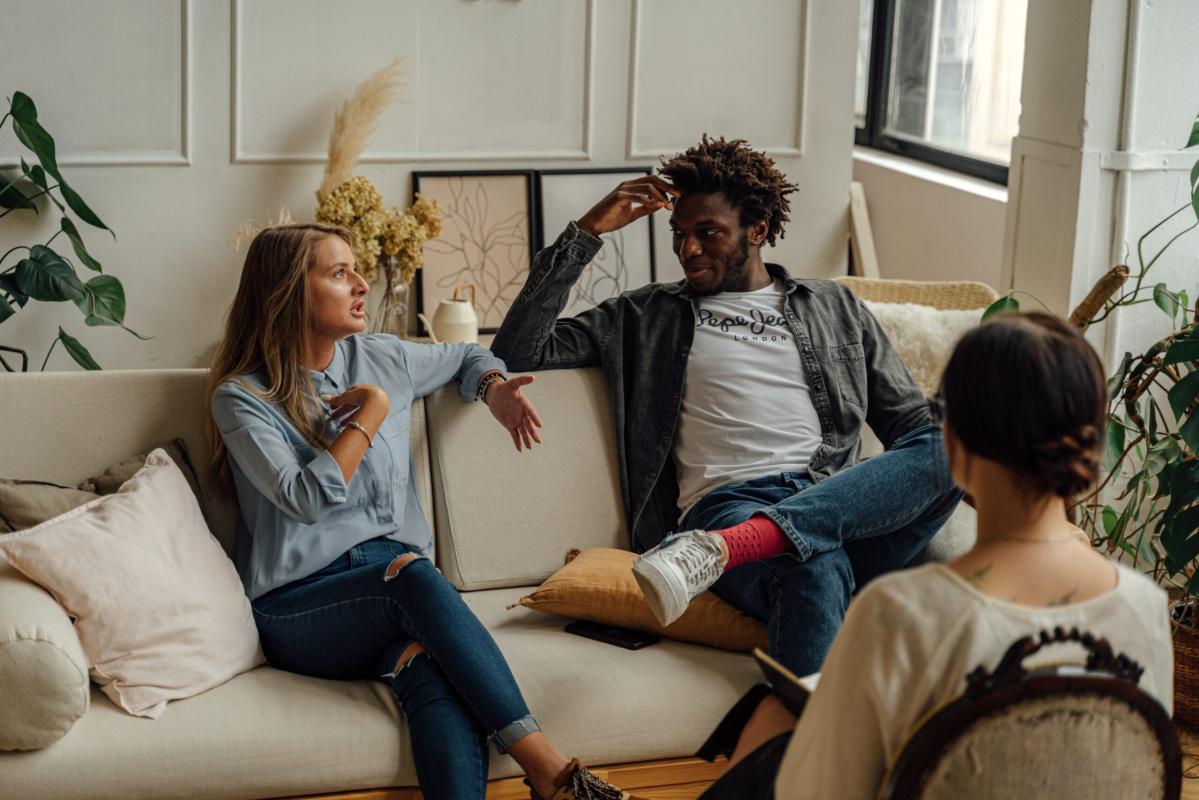 Group of people sitting on a couch talking.